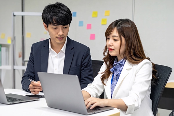 パソコンを開いて打ち合わせする男性と女性